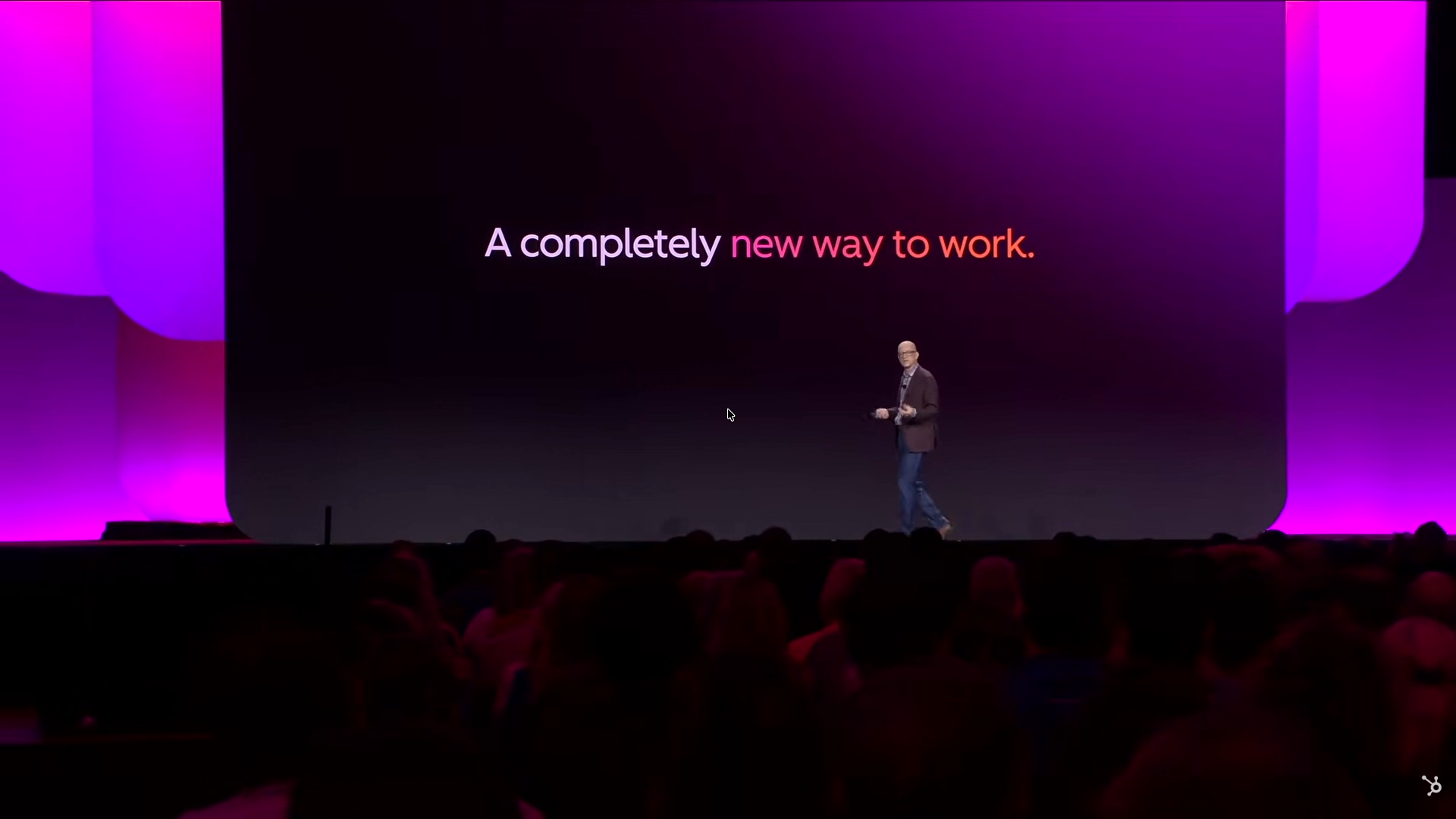 Stage screen displaying the text A completely new way to work with the presenter standing to the side
