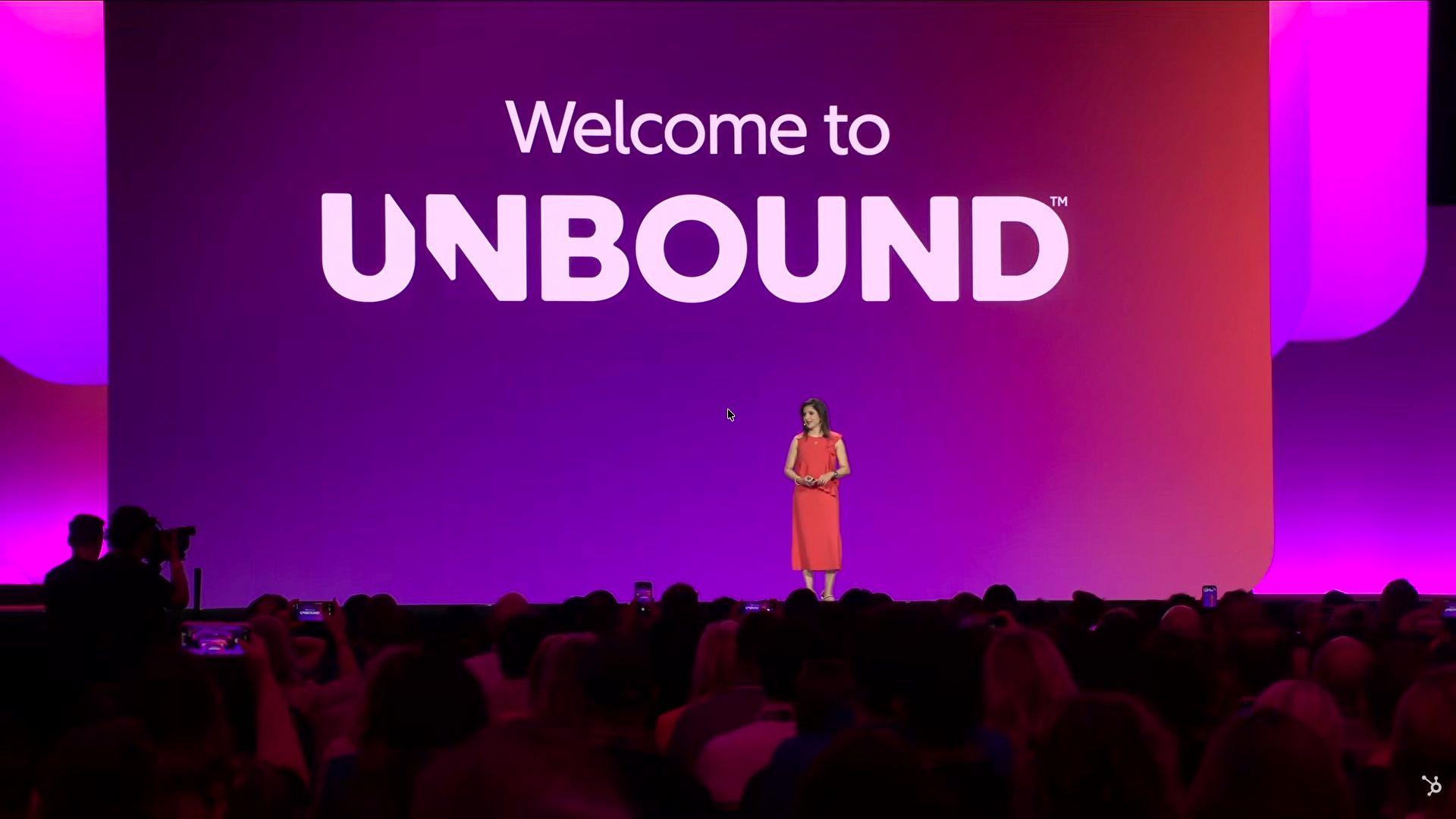 Stage with a purple and pink gradient backdrop reading Welcome to UNBOUND, with the keynote speaker on stage