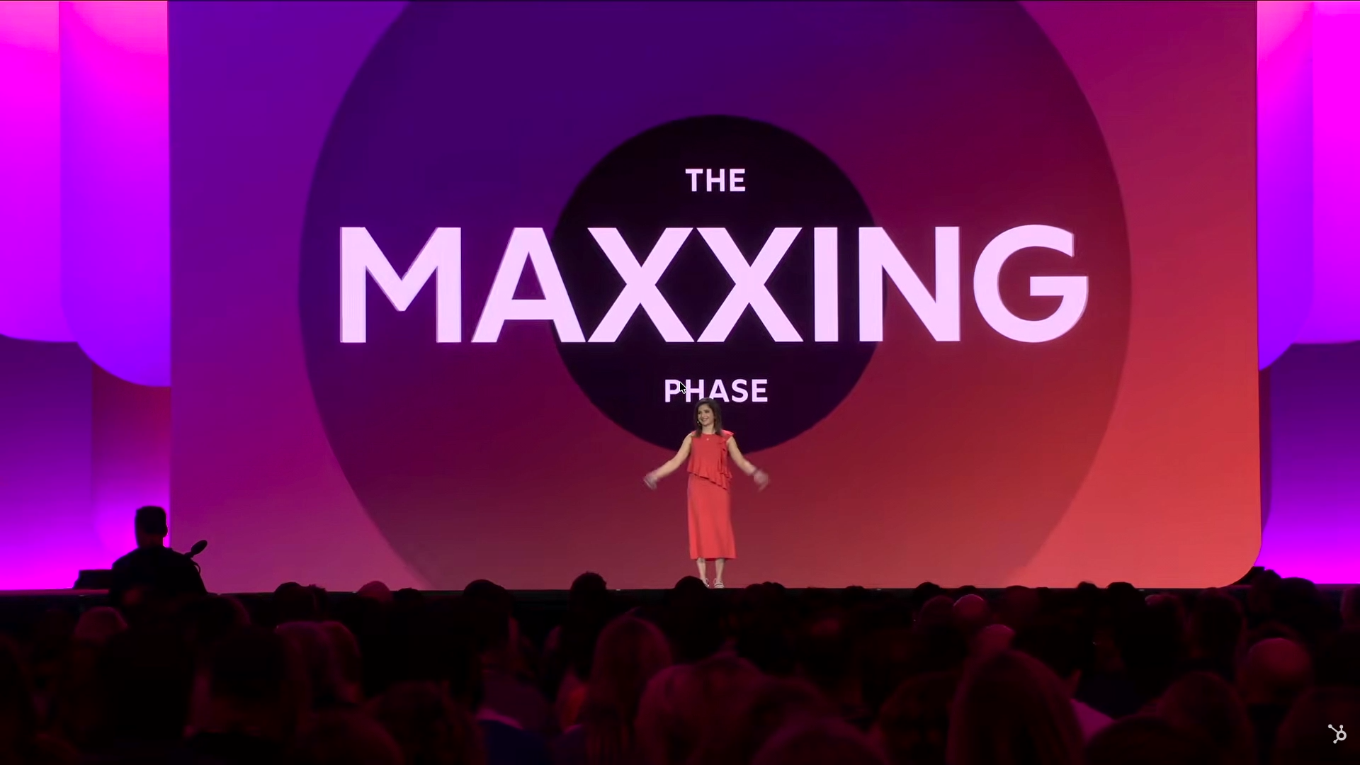 Stage backdrop reading THE MAXXING PHASE in bold white letters with the speaker standing in front