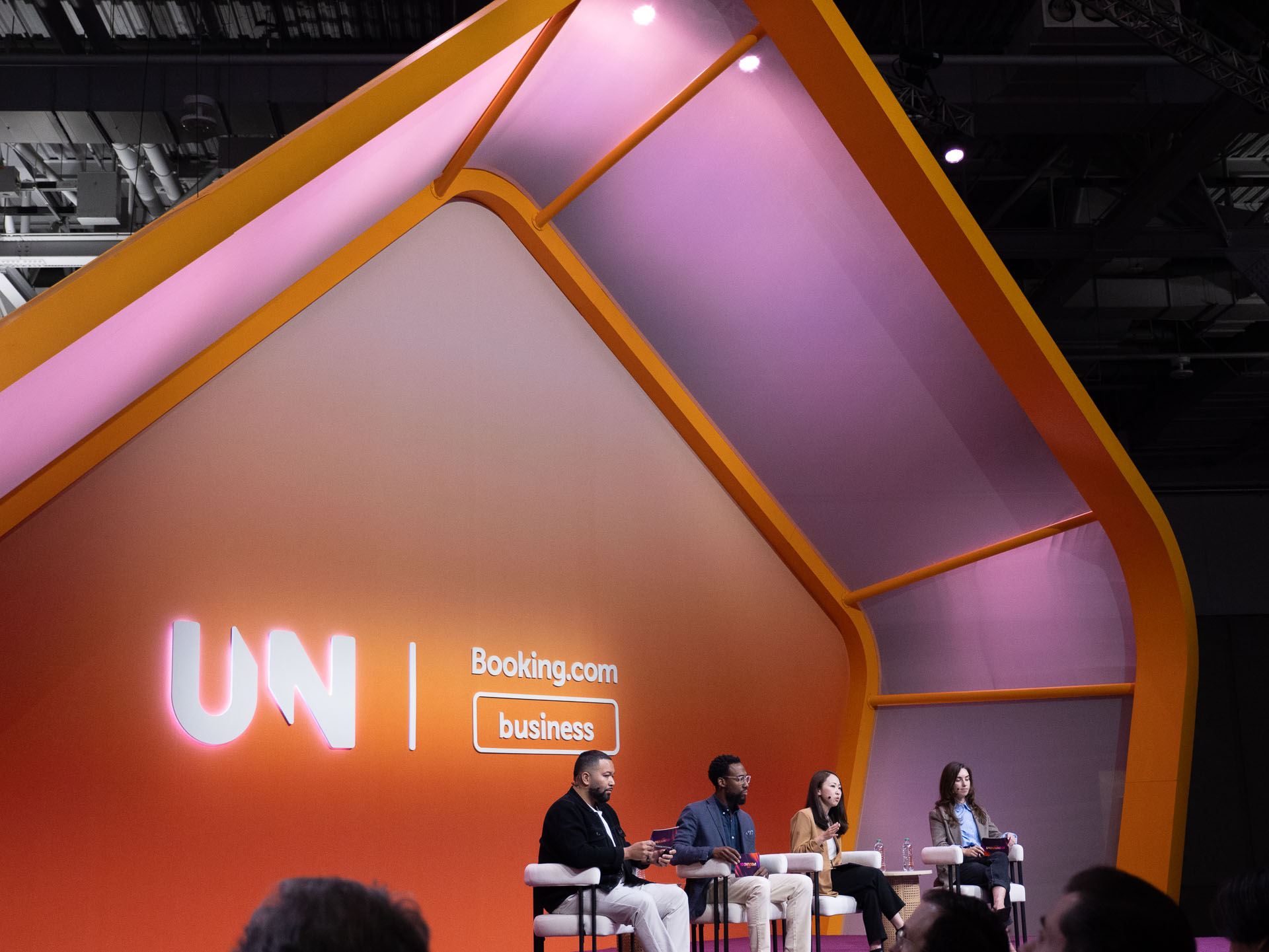 Stage set shaped like a stylised house in orange and pink tones with a large illuminated logo to the left
